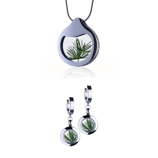 Pine Needles Jewelry Set with a designer necklace by Barbora-Adamonyte Keidune and dangle huggie earrings in stainless steel, featuring real pine needles under glass. Symbolizes eternal vitality and boundless optimism.