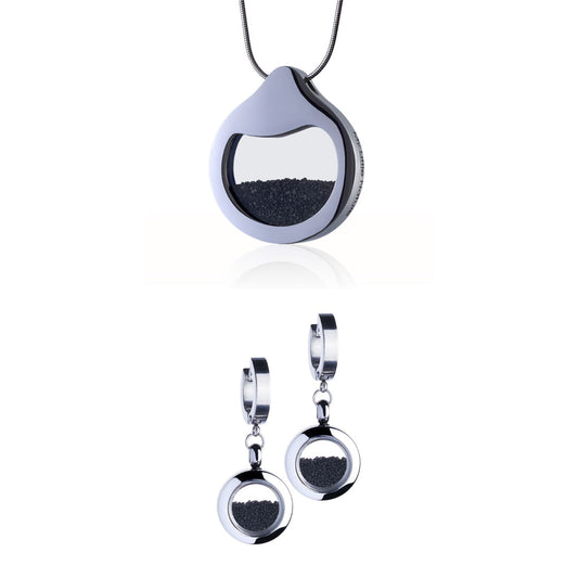 Volcanic Sand Jewelry Set with a designer necklace by Barbora-Adamonyte Keidune and dangle huggie earrings in stainless steel, featuring real volcanic sand under glass. Symbolizes strength and transformation

