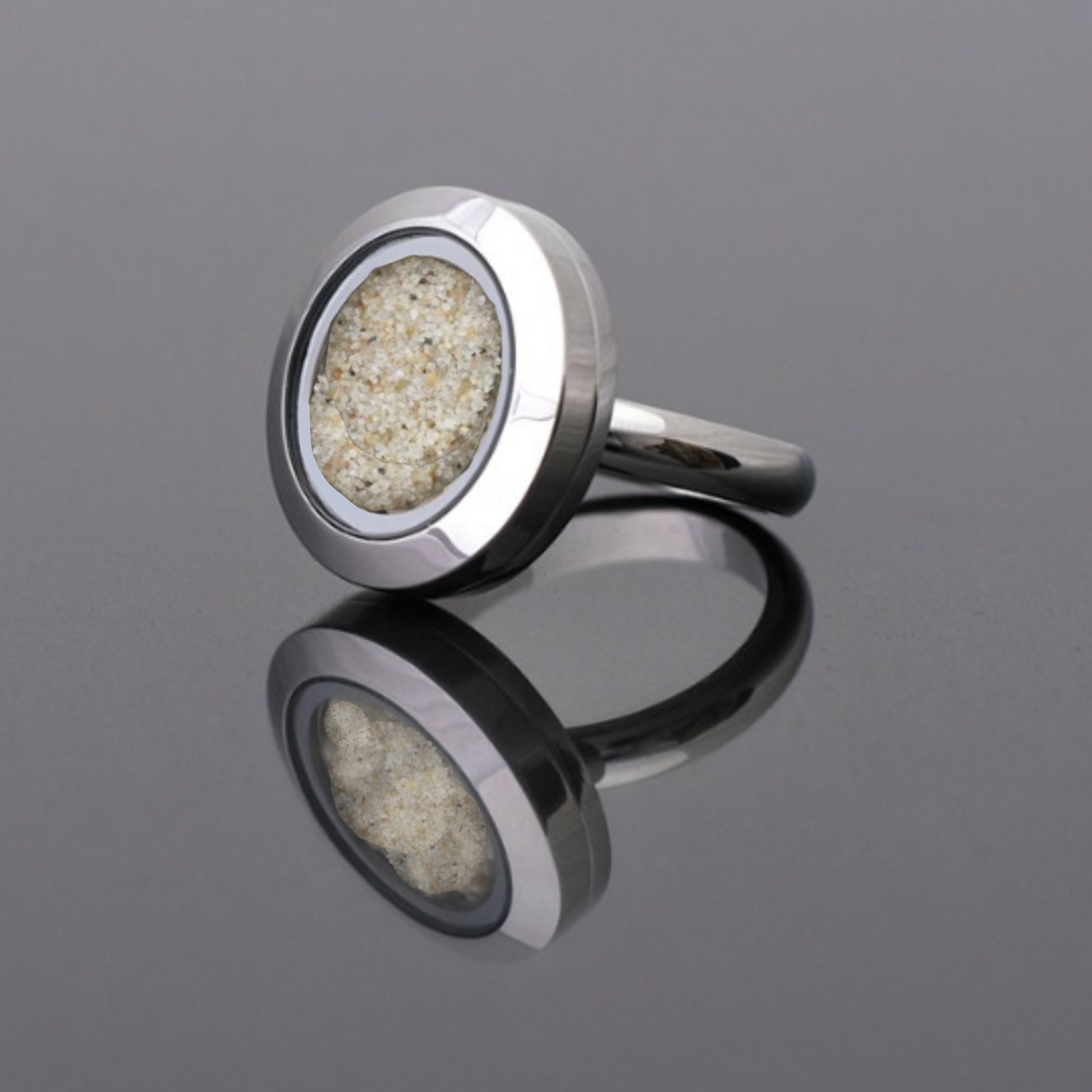 Handmade statement ring with real beach sand preserved under glass, set in a stainless steel band, symbolizing serenity and timeless beauty.