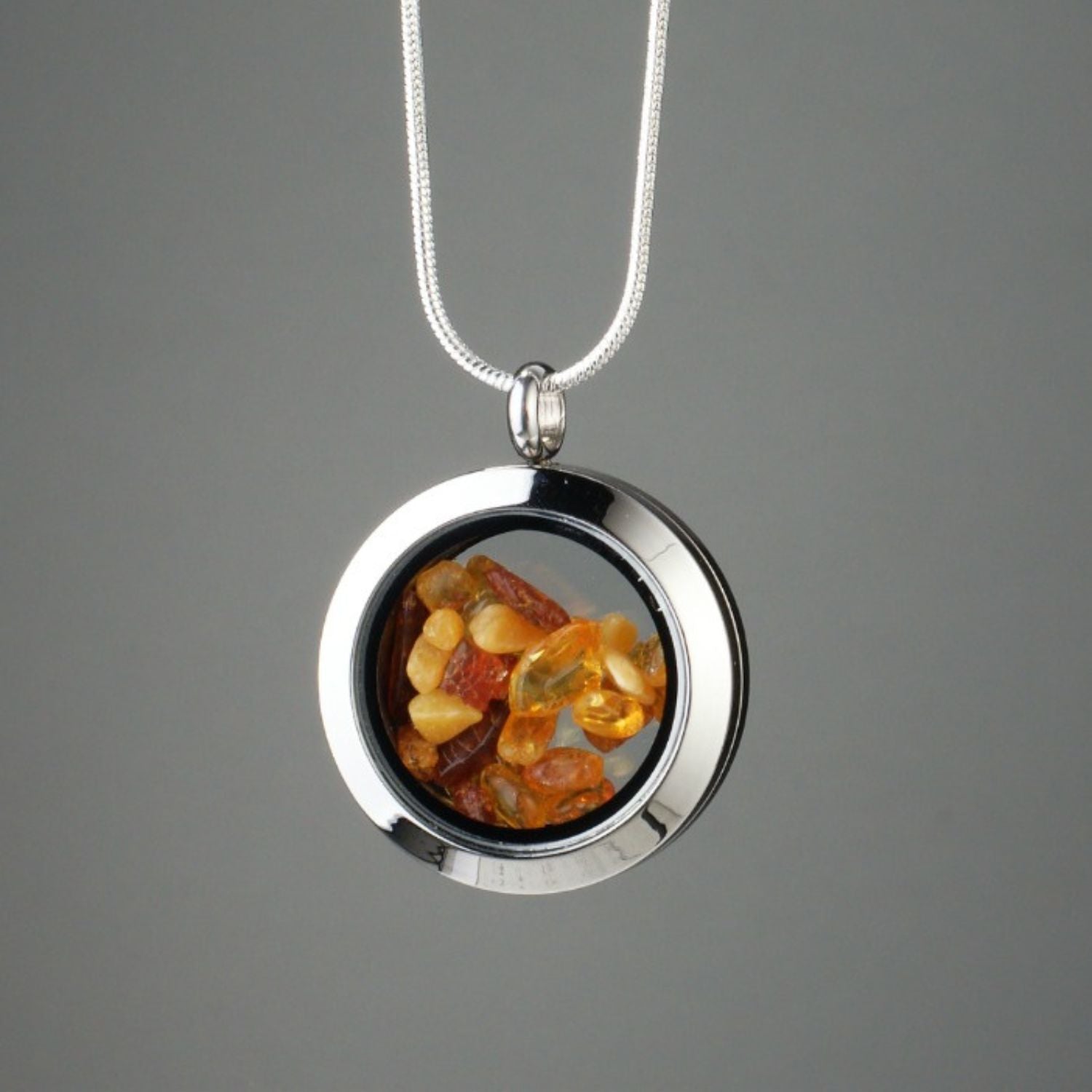 Handmade amber amulet with natural amber encased in glass, set in stainless steel.