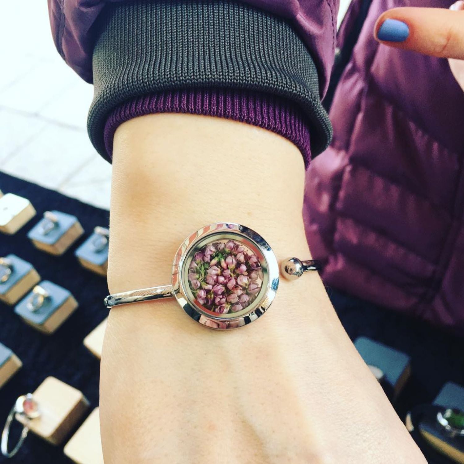 Handmade cuff bracelet with real heather flowers encased under glass, symbolizing endurance and healing.