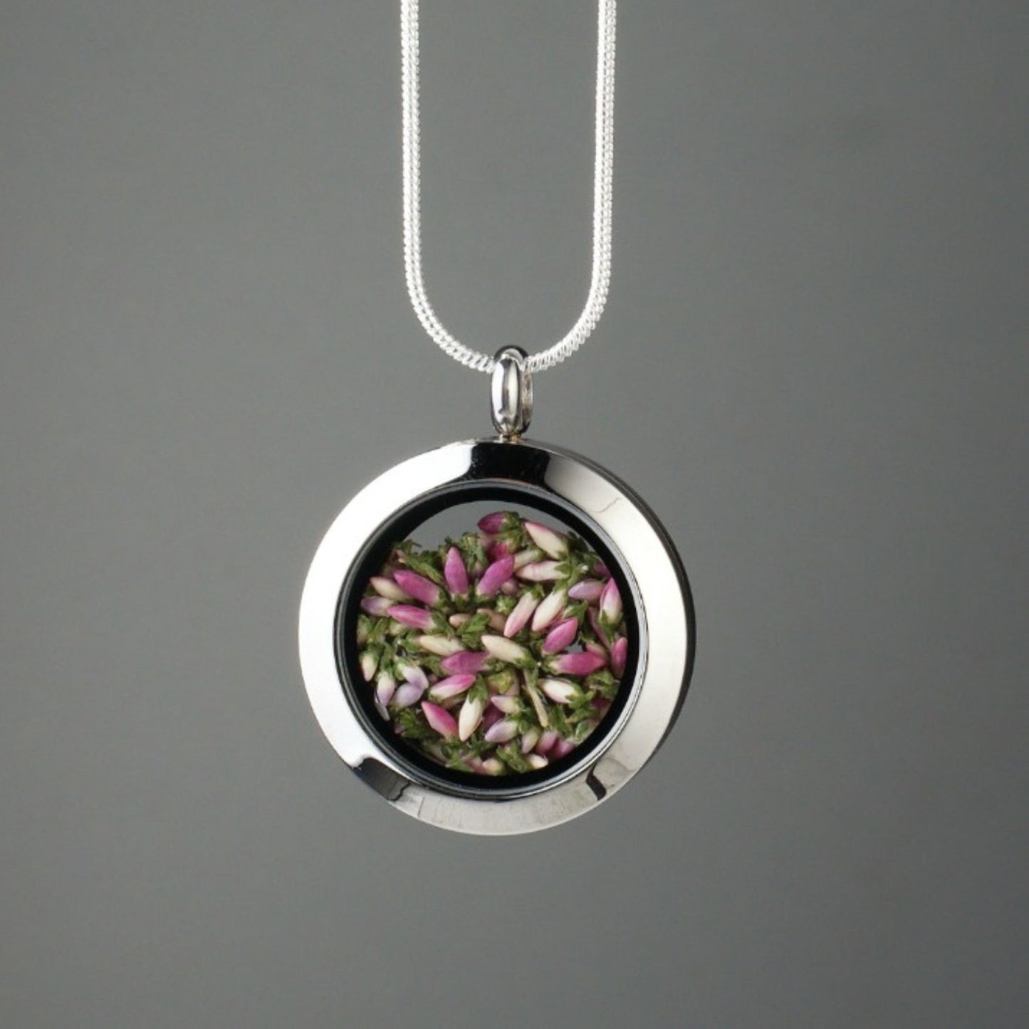 Handmade heather amulet with real heather encased in glass, set in stainless steel.