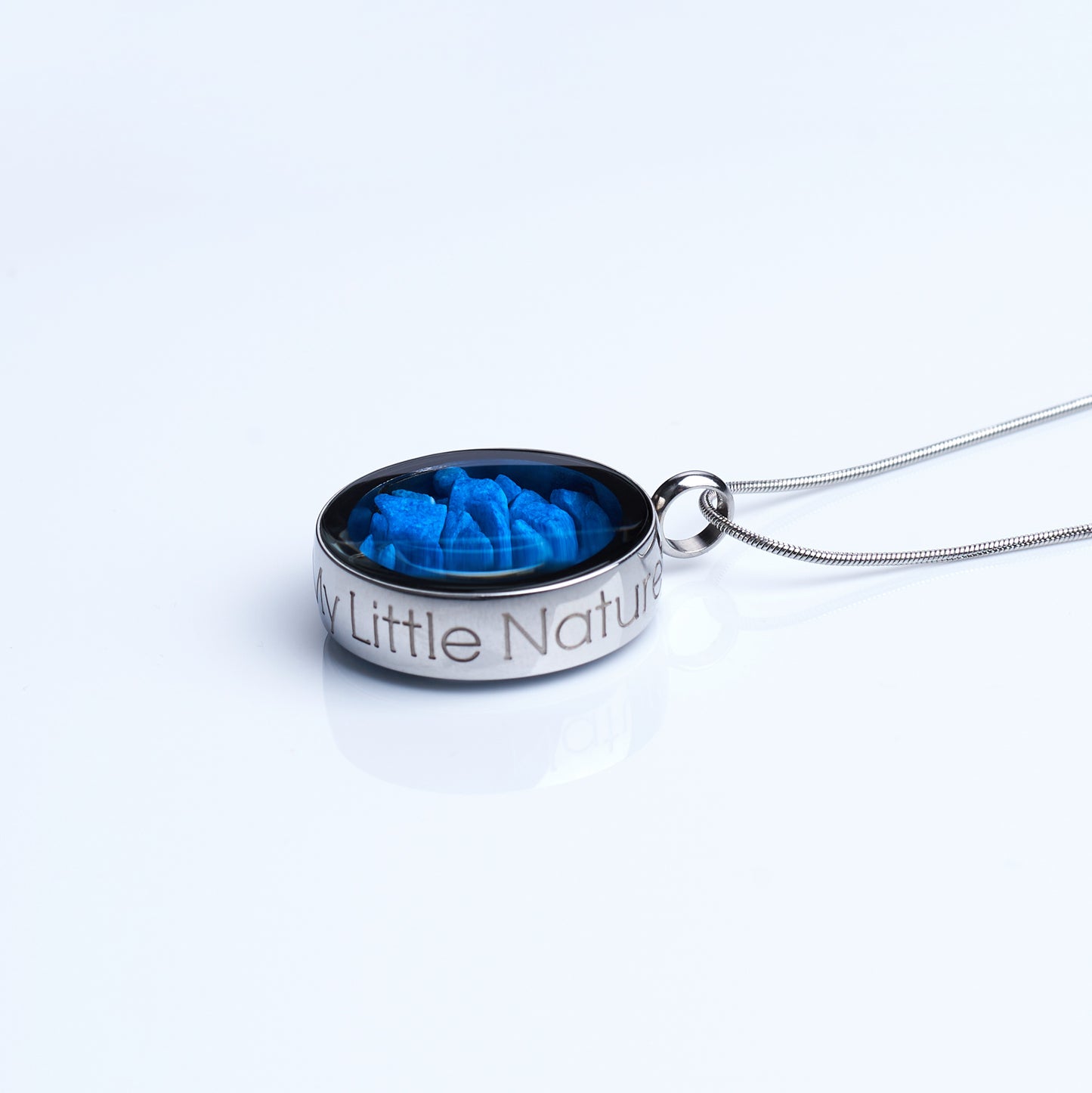 Handmade magnified blue stones necklace featuring genuine blue stones under a glass lens, symbolizing resilience, strength, and inner power. Nature-inspired jewelry piece side