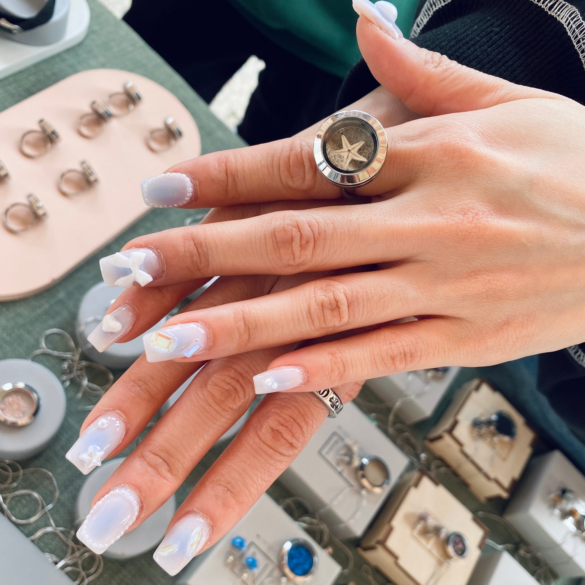 hand with ring on a finger with starfish and sand ring 