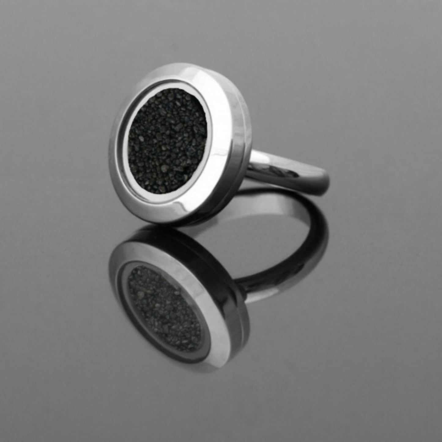 Handmade statement ring with real volcanic sand preserved under glass, set in a stainless steel band, symbolizing resilience and inner strength.