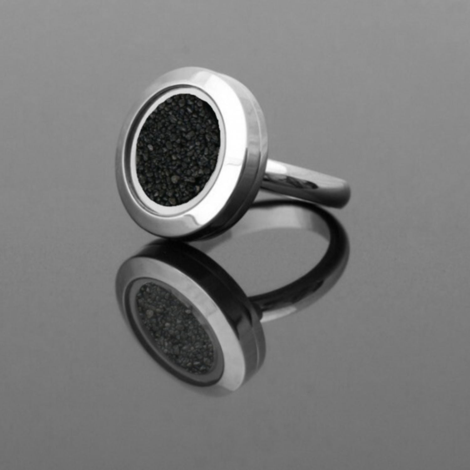 Handmade statement ring with real volcanic sand preserved under glass, set in a stainless steel band, symbolizing resilience and inner strength.